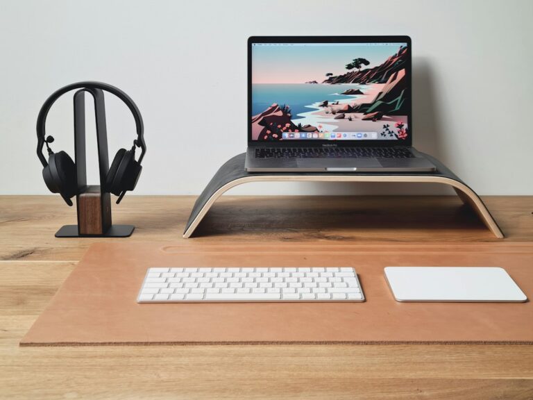 Headphones on a stand beside a laptop on a desk