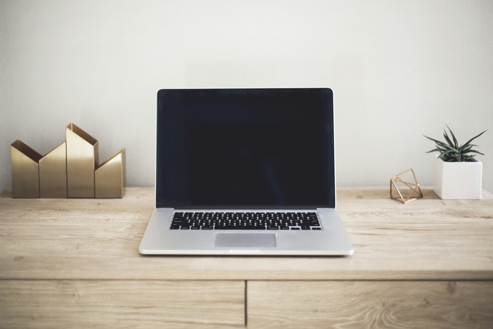 A laptop on a wooden desk for organizing customer feedback