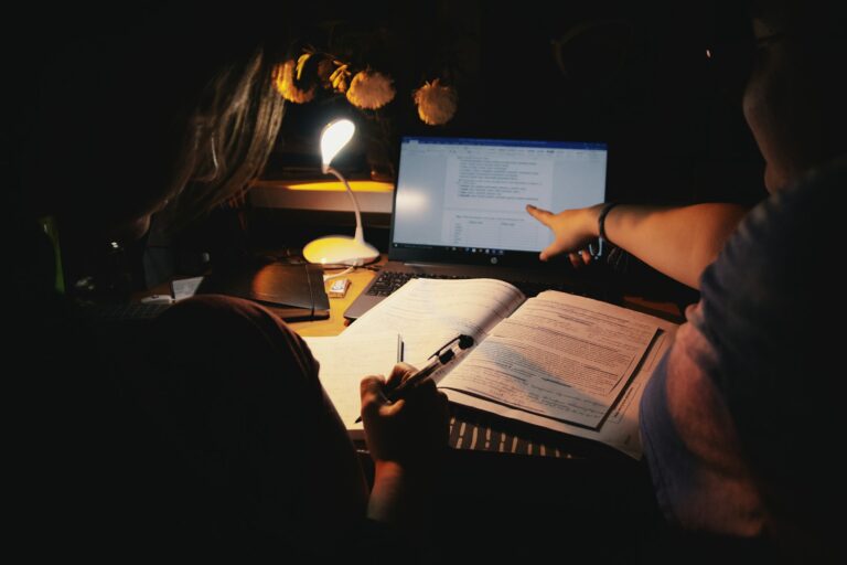 Students reviewing notes and a worked example beside a laptop