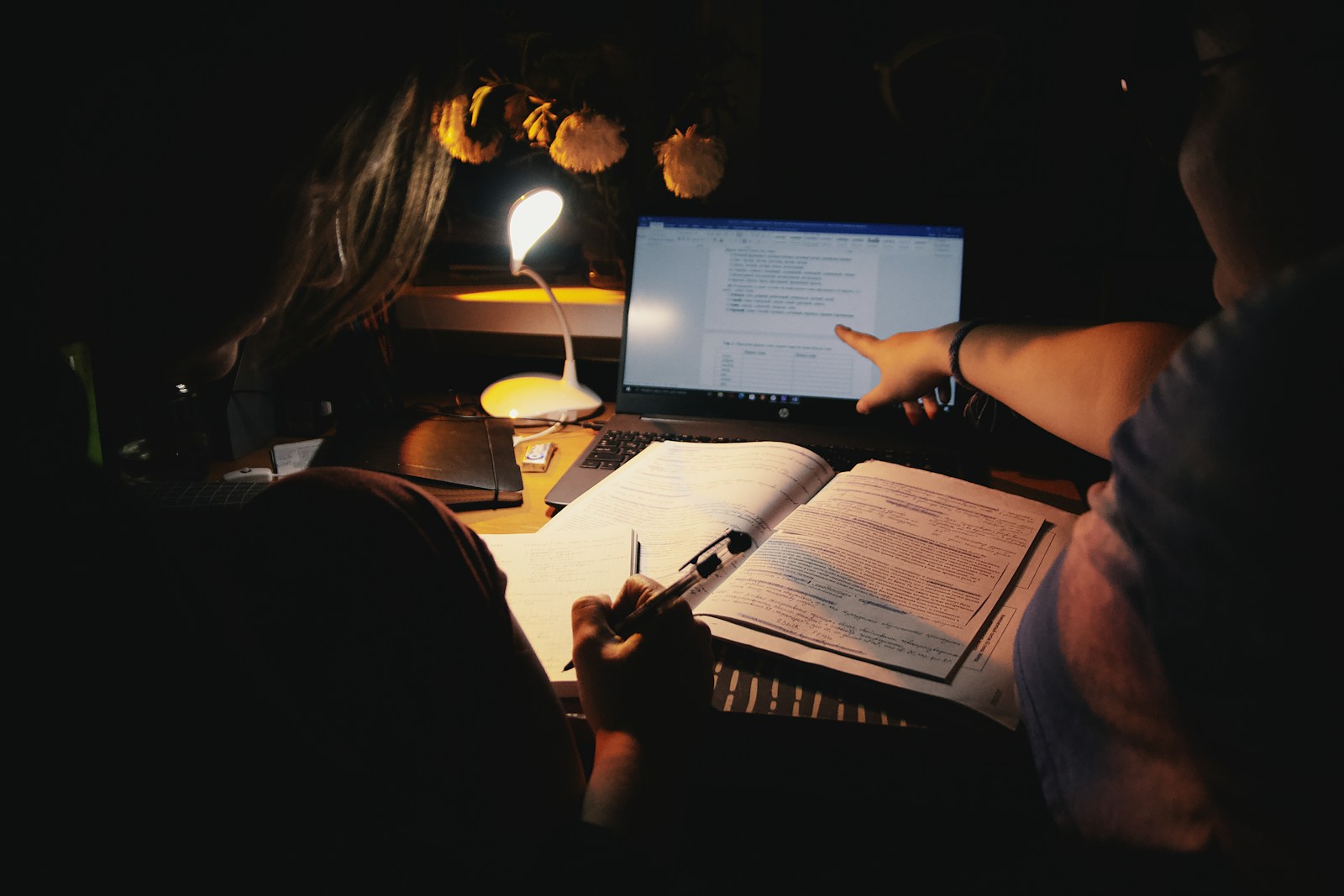 Students reviewing notes and a worked example beside a laptop