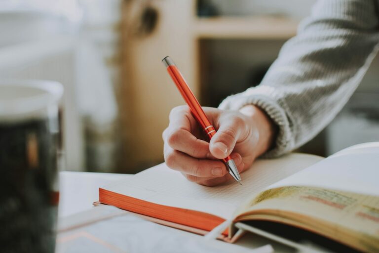 A person using a pen to write in a notebook